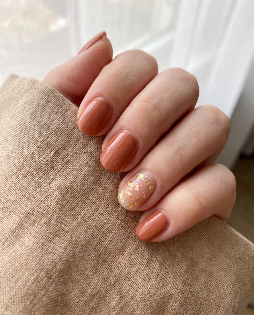 Manicure met warme terracotta gelpolish en een fijn goudkleurig accentdetail